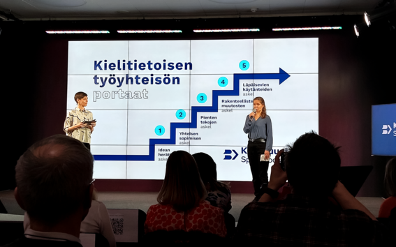 A photo of the Launch of kielibuusti.fi online portal event with an image of Steps Towards Language Awareness in the Workplace.
