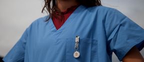 A woman in a nurse's work clothes.